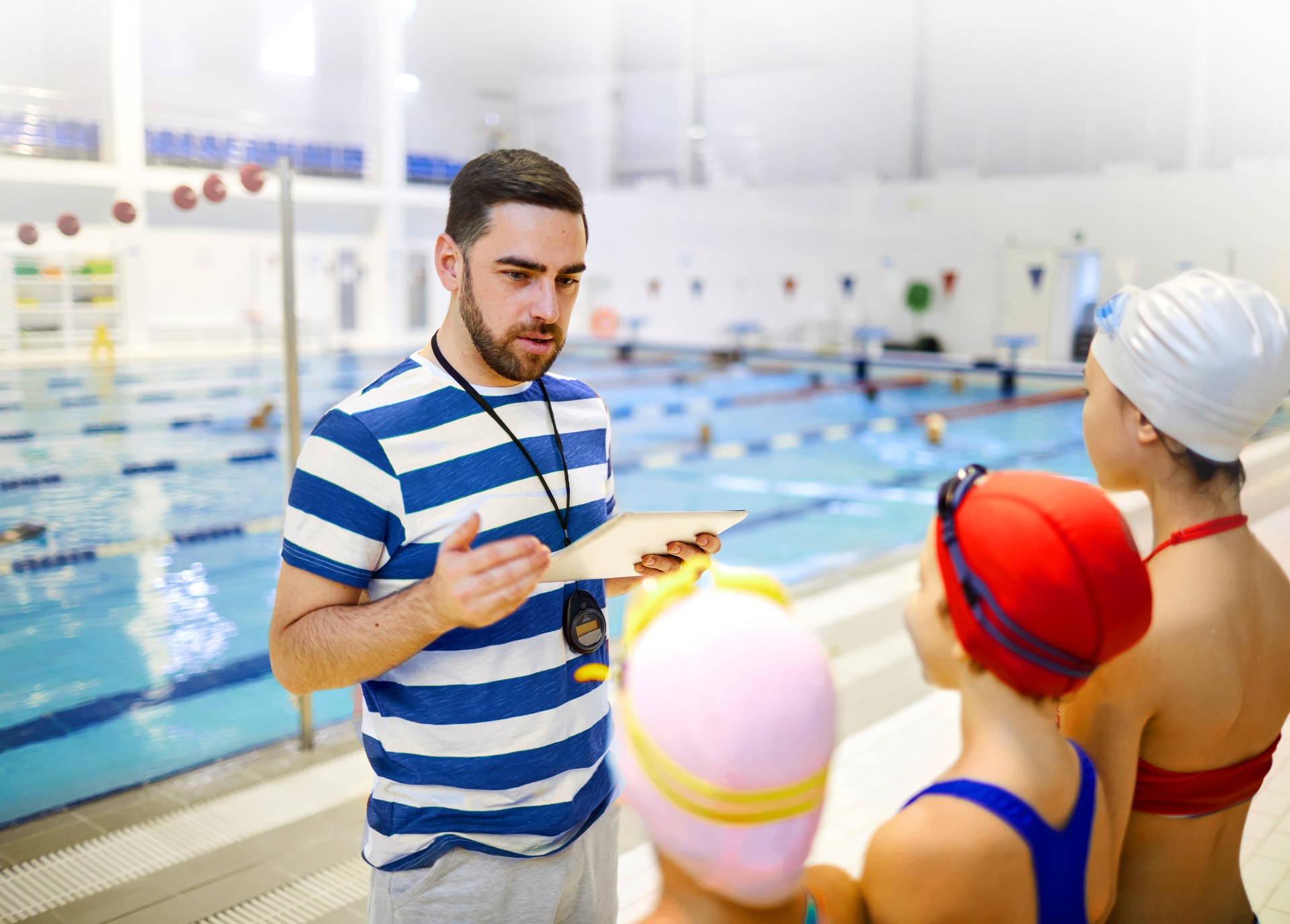 Instructor talking with young swimmers at the poolside